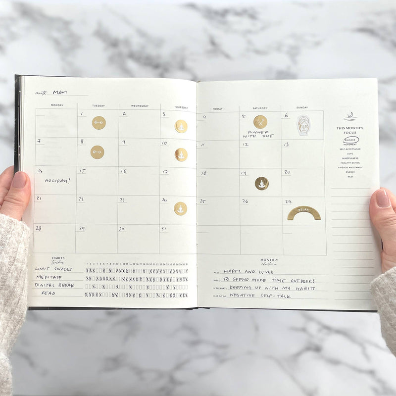 Open planner with celestial designs on a marble surface