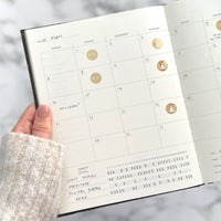 Calendar page in a planner held by a hand with a blurred background