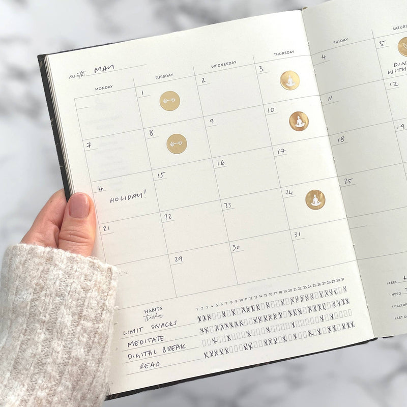 Calendar page in a planner held by a hand with a blurred background