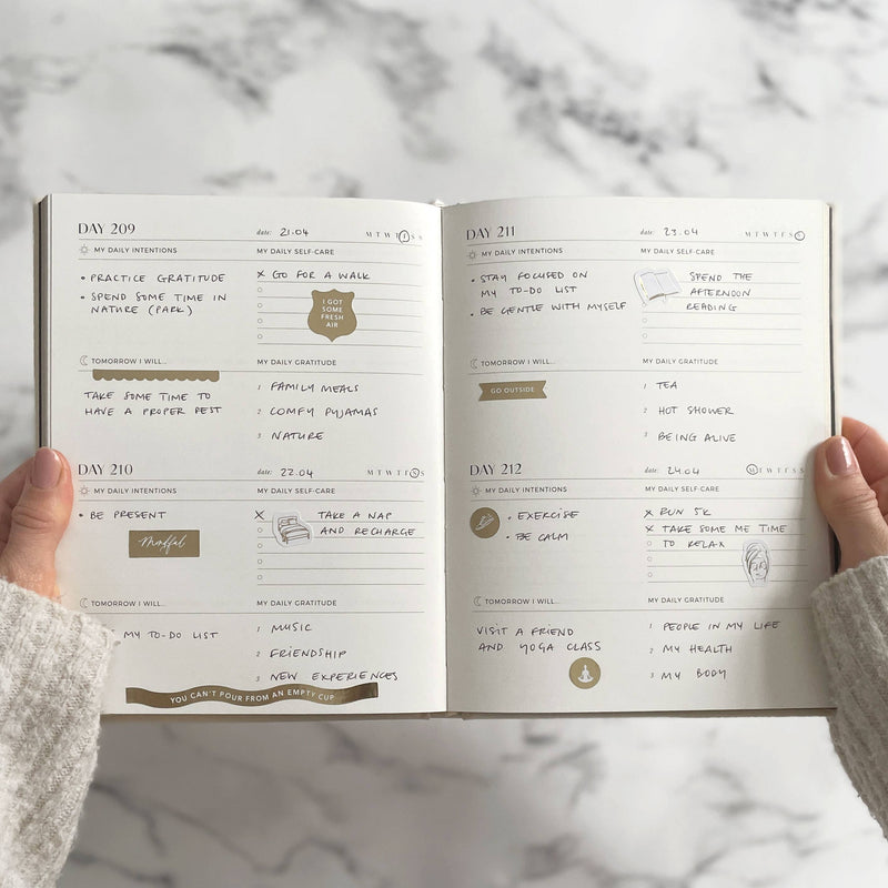 Open planner with daily entries on a marble surface