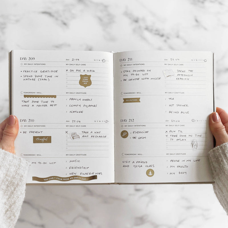 Open planner with daily entries on a marble surface