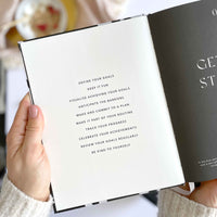 Hand holding an open book with motivational text on a blurred background