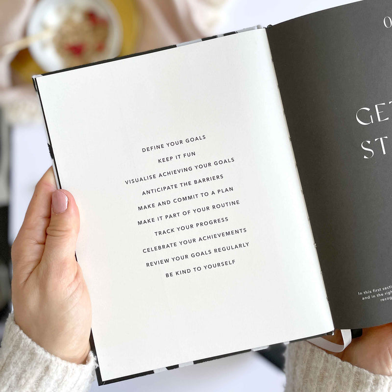 Hand holding an open book with motivational text on a blurred background