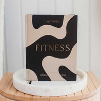 Journal titled 'My Daily Fitness' on a marble coaster with a white background