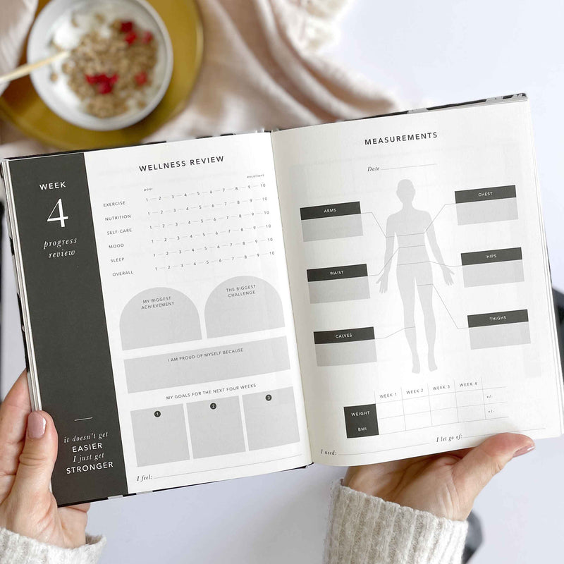 Person holding an open book with wellness review and measurements pages.