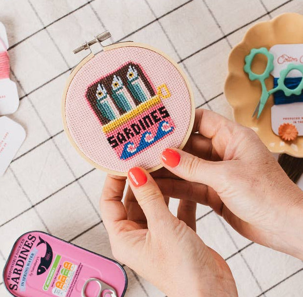  cross-stitch kit with 'Sardines' design on a tiled surface.