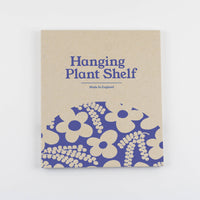 Hanging plant shelf packaging with blue floral design and text on a beige background